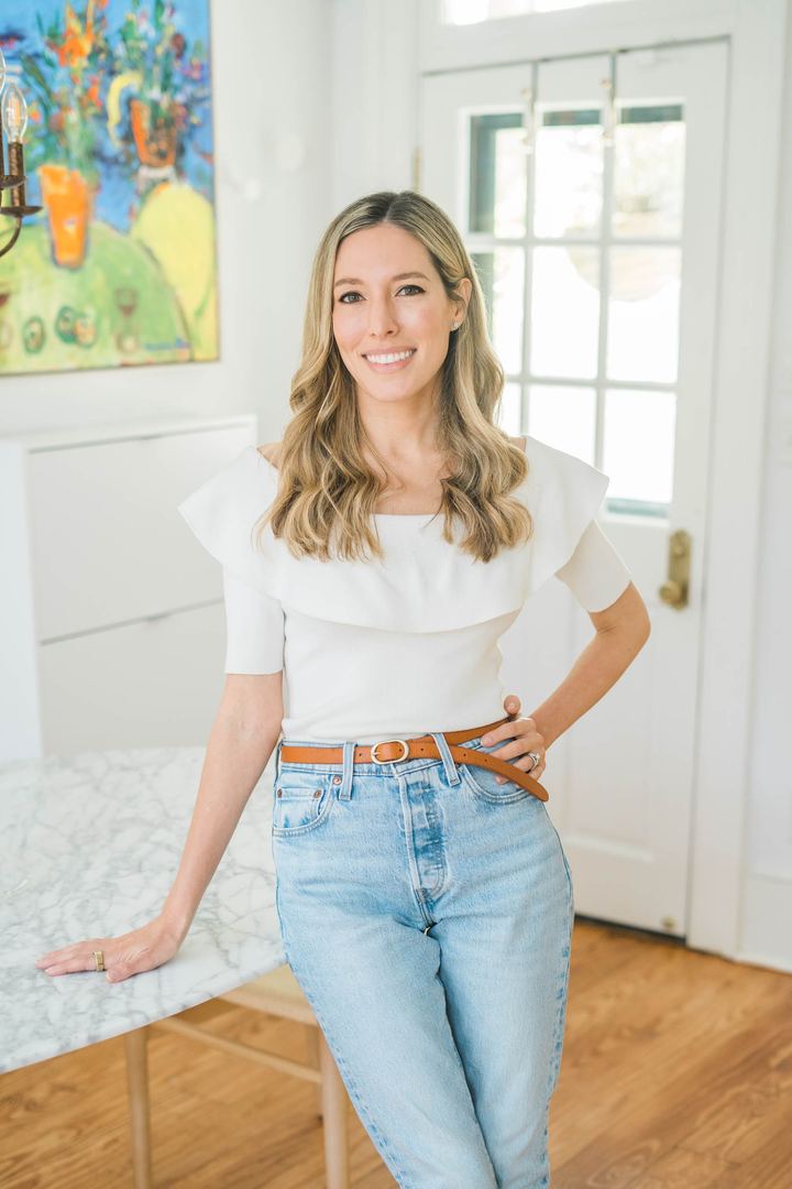 Tamara Ashworth standing with one hand on her hip beside a marble table, smiling at the camera.